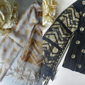 Puede incluir: Dos bufandas, una con fondo blanco y lunares dorados y un patr&oacute;n de chevron, y la otra con fondo negro y lunares dorados y un patr&oacute;n de chevron.