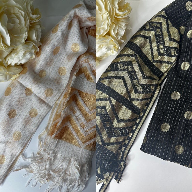 Puede incluir: Dos bufandas, una con fondo blanco y lunares dorados y un patr&oacute;n de chevron, y la otra con fondo negro y lunares dorados y un patr&oacute;n de chevron.