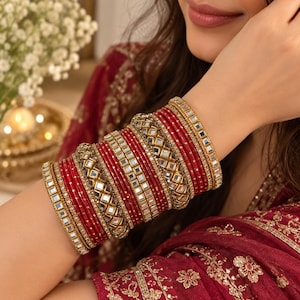 May include: A stack of red bangles featuring gold-toned metal accents and square mirror inlays. The set includes multiple thin red bracelets interspersed with wider bands that have reflective square mirror pieces and intricate gold-colored metal detailing.