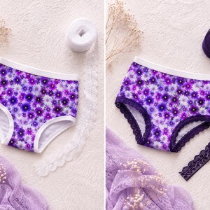 May include: Floral print underwear with a white trim and a purple floral pattern. The underwear is surrounded by white lace, purple lace, and a purple scarf. The underwear is a high-waisted style.