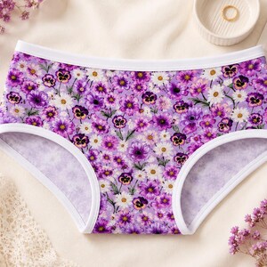 May include: Floral print underwear with a white trim. The underwear features a pattern of purple and white flowers on a light purple background. The underwear is made of a soft, comfortable material.