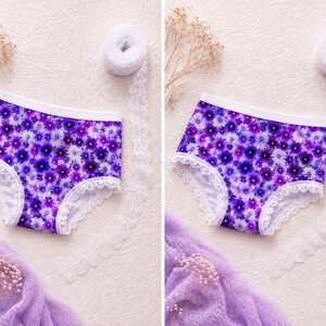 May include: A pair of purple floral print underwear with white lace trim. The underwear features a pattern of purple and white flowers. The waistband is white. The background is a light beige color.