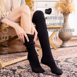 May include: A pair of black over-the-knee socks made of lambswool. The socks are ribbed and have a cozy look. The text "SUPER COZY LAMBSWOOL OVERKNEE SOCKS" is visible in the image.