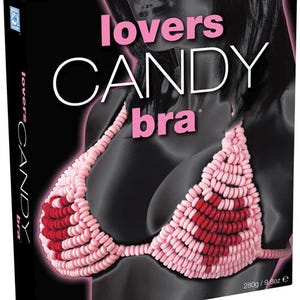 May include: A black box featuring a candy bra made of pink and red candies. The words "lovers CANDY bra" are in pink and white text. The box also has a silhouette of a person.