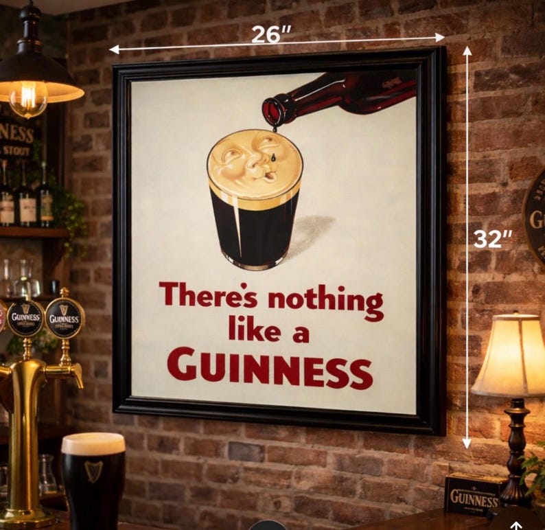 May include: A framed Guinness advertisement, 26 inches wide and 32 inches tall, features a pint of stout being poured from a bottle. The text reads "There's nothing like a Guinness" in red. The image is set against a brick wall.