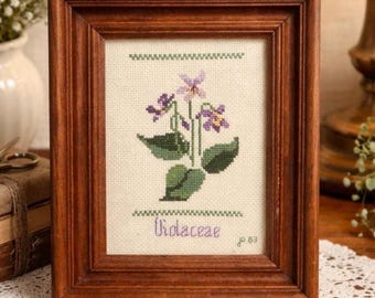 Arte mural botánico vintage en punto de cruz – Bordado floral enmarcado «Violaceae» – Decoración natural de estilo rústico
