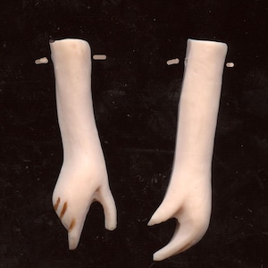 May include: Two pale, sculpted arms with hands, positioned against a dark background. The arms are smooth, with subtle details in the hands, including slight discoloration. The hands are in a relaxed, open position, suggesting a delicate or artistic theme.