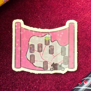 May include: A pink sticker with a map design. The map features a light gray landscape with several dark gray rectangular structures connected by red lines. A black silhouette of a carriage is at the bottom. The sticker has a holographic effect.