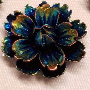 May include: A blue, green, and gold iridescent flower-shaped button with a textured surface.