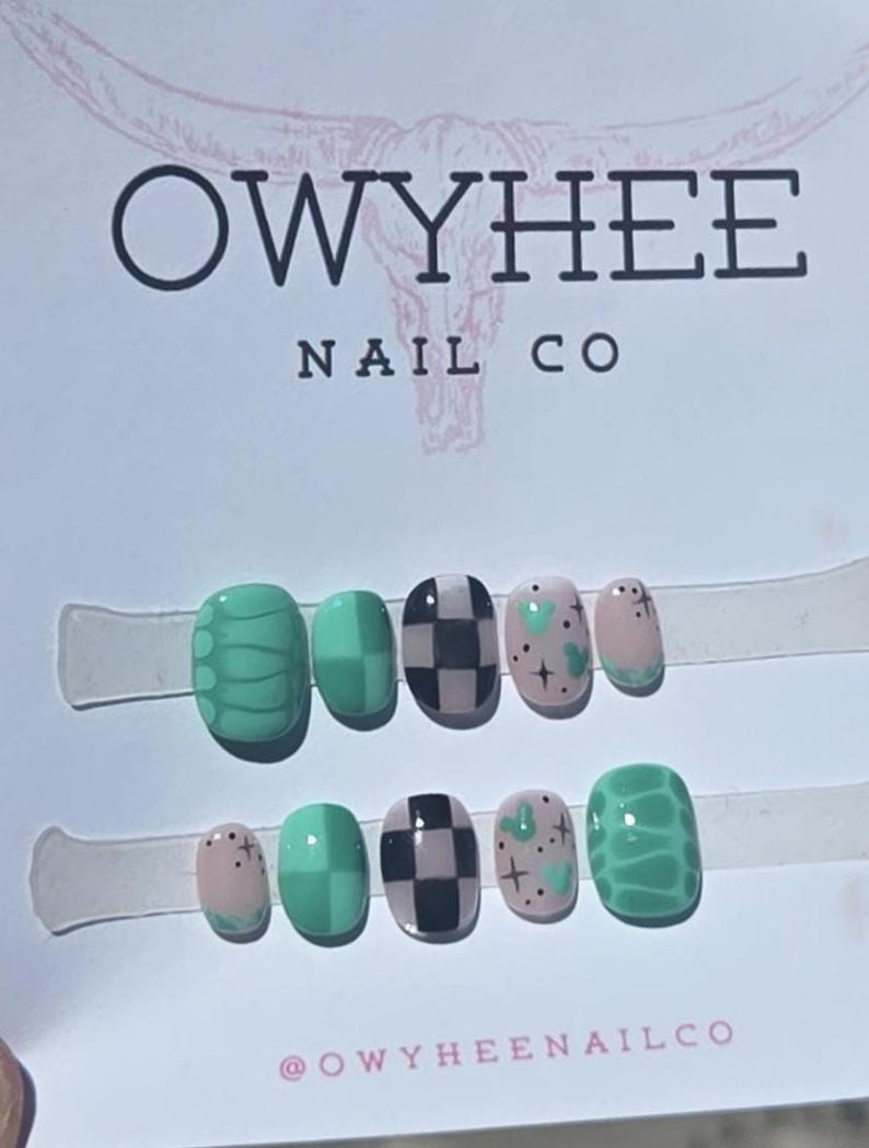 May include: A set of ten press-on nails displayed on a white card labeled OWYHEE NAIL CO. The nails feature various designs including green snake skin patterns, solid green squares, black and white checkerboards, and light pink with green hearts.