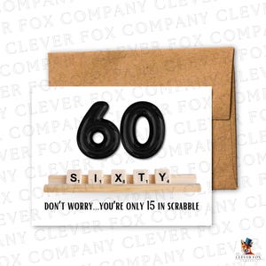 May include: A white birthday card with a brown envelope. The card displays the number 60 in black, Scrabble tiles spelling "SIXTY", and the text "DON'T WORRY...YOU'RE ONLY 15 IN SCRABBLE".