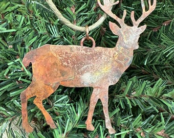 May include: A rustic copper deer ornament with a distressed finish. The deer is hanging from a twine string and has a loop at the top for hanging.