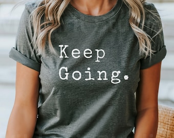 May include: A dark gray t-shirt with the text "Keep Going." printed in white.