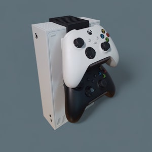 May include: A white Xbox Series X console with a black and white controller stand. Two controllers are attached to the stand, one white and one black.