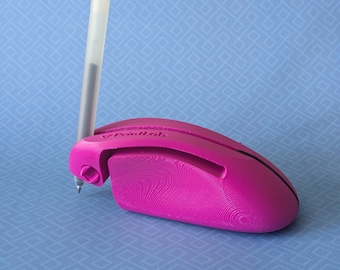 May include: A pink 3D printed pen holder with the word "Printlab" on the side. The holder is designed to hold a pen or pencil vertically.