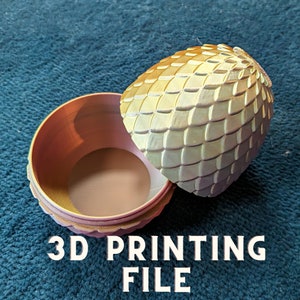 Puede incluir: Una caja de joyas de huevo de dragón impresa en 3D con un acabado dorado e iridiscente. La caja está abierta, revelando el interior. El texto "3D PRINTING FILE" es visible debajo de la caja.