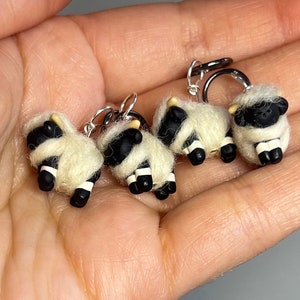 May include: Four black and white sheep stitch markers with silver rings. The sheep are made of wool felt and have black faces and legs.