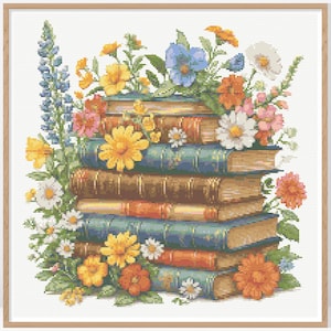 May include: A cross-stitch design depicting a pile of books decorated with vibrant flowers. The books have blue, brown, and orange spines. The flowers include yellow, orange, white, and blue blooms, with green leaves. The artwork is framed in a light wood frame.