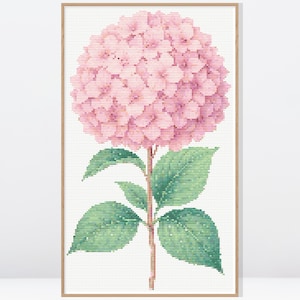 May include: A framed cross-stitch of a pink hydrangea flower. The flower head is a large, round cluster of small pink blossoms. The green leaves and stem are detailed with cross-stitch. The artwork is set against a white background.