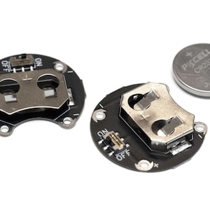 May include: Two black circuit boards with a battery holder and an on/off switch. A silver CR2032 battery is also shown.