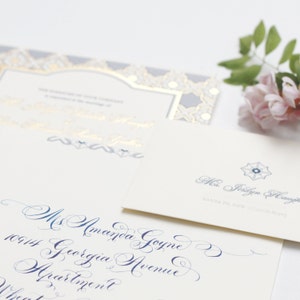 May include: A white envelope with blue calligraphy that reads "Ms Amanda Goyne, 10914 Georgia Avenue, Apartment". A smaller white envelope with a blue and white floral design and the text "Ms. Jocelyn Haught, SANTA FE, NEW MEXICO 87501" is on top of the larger envelope.