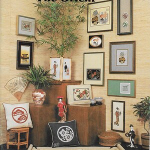 May include: A collection of needlepoint and cross-stitch designs inspired by Asian culture. The designs feature traditional Japanese motifs like cherry blossoms, pagodas, and geishas. The text on the image reads "This is... "The Orient"  Charted Designs for Needlepoint and Cross-Stitch Designed by Ulla Baroness von Schoeler"