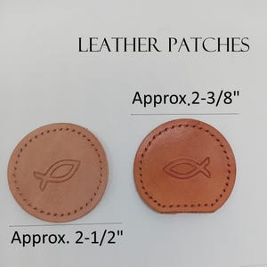 May include: Two brown leather patches with a stitched edge and a fish symbol in the center. The patches are approximately 2-1/2 inches in diameter.  LEATHER PATCHES Approx. 2-3/8"