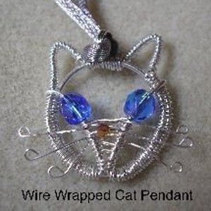 Op de afbeelding: Een zilveren draadgewikkelde kattenhanger met blauwe glazen ogen en een bruine draadneus.