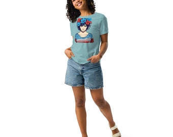 Puede incluir: Una mujer con una camiseta azul claro con un gráfico de una mujer con flores en el pelo. También lleva pantalones cortos de mezclilla y sandalias blancas.