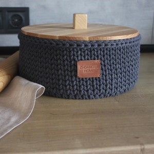 May include: A grey knitted storage container with a wooden lid and a brown leather label that reads "ZHDANOVA HOME".