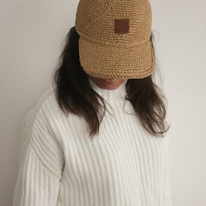 May include: A brown crocheted baseball cap with a brown leather patch on the front.