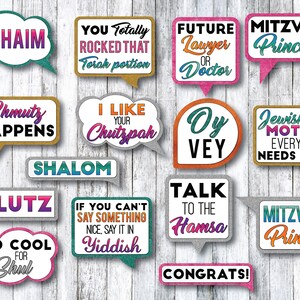 May include: A set of 15 colorful photo booth props with glitter accents and Jewish-themed sayings. The props include phrases like "L'Chaim", "Shmutz Happens", "Oy Vey", "Talk to the Hamsa", and "Mazel Tov".