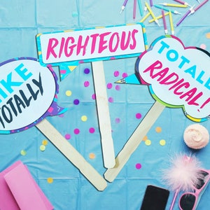 May include: Three colorful cardboard signs with sticks attached, featuring 90s slang phrases: "Like Totally", "Righteous", and "Totally Radical!"