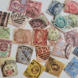 Pode incluir: Uma coleção de selos postais vintage em várias cores, incluindo vermelho, verde, roxo e azul. Os selos apresentam desenhos e textos intrincados, alguns com carimbos postais e datas. Os selos estão dispostos sobre uma superfície branca.