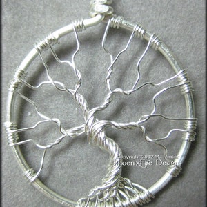 May include: A silver wire tree of life pendant with a circular frame and a twisted wire trunk. The pendant is made of wire and has a delicate, intricate design. Copyright 2012 M. Turner PhoenixFire Designs.