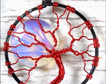 Puede incluir: Pendiente de árbol de la vida envuelto en alambre rojo con una piedra de ópalo iridiscente transparente. El pendiente está hecho de alambre negro y alambre rojo. Copyright 2013 M. Turner PhoenixFire Designs.