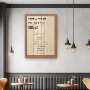 Könnte beinhalten: Ein gerahmtes Schild mit einem Hintergrund aus Sackleinen und einem braunen Holzrahmen. Das Schild lautet "Mach eine Pause, du musst dich entspannen mit einer Tasse" und listet verschiedene Kaffeesorten auf. Das Schild hängt an einer Wand in einem Café.