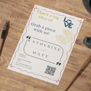May include: A cream-colored wedding invitation with red and gold accents. The invitation features the text "That's a big slice of" and "Grab a piece with us!" along with the names "Katherine and Matt". Includes a pizza graphic and a QR code.