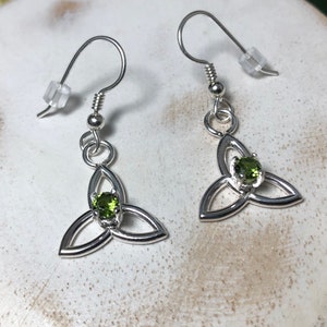 May include: Silver earrings with a green gemstone in the centre of a Celtic knot design.