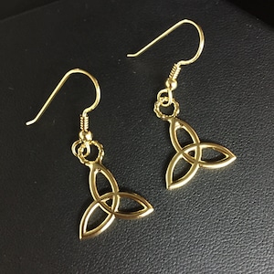 Könnte beinhalten: Ein Paar goldfarbene Ohrringe mit einem keltischen Knotendesign. Die Ohrringe sind im Hänge-Stil mit einem Hakenverschluss.