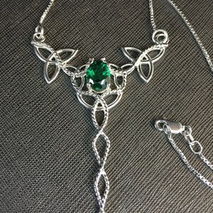 May include: A silver Celtic knot necklace with a green gemstone pendant. The necklace features a delicate chain and a detailed knot design.