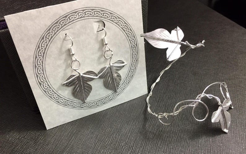 May include: Silver leaf earrings and a matching silver leaf bracelet. The earrings are dangle earrings with two leaves on each earring. The bracelet is a delicate wire bracelet with a single leaf charm.