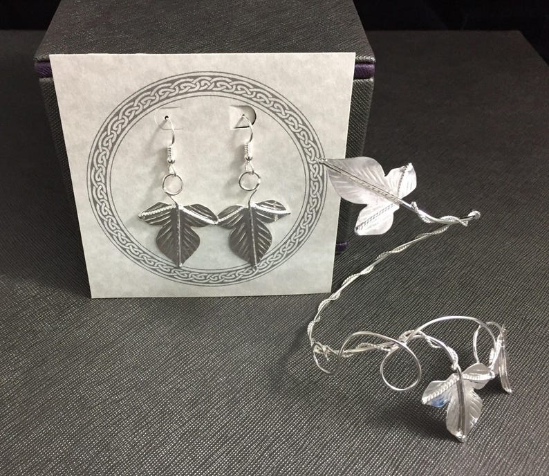 May include: A pair of silver earrings with leaf designs and a silver leaf headband.
