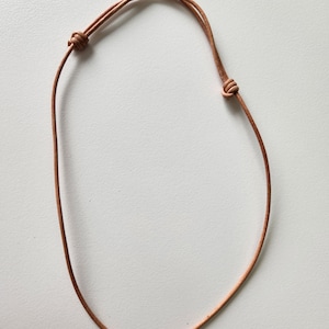 May include: A simple brown leather cord necklace with a knotted closure.