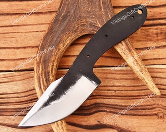 May include: A black knife blade with a silver edge, resting on a brown antler against a wooden background. The knife has a curved blade and a handle with three holes. The words "VikingsGiftCraftsUsa" are printed on the background.