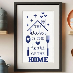 Könnte beinhalten: Gerahmtes Kreuzstich-Kunstwerk mit dem Text "The kitchen is the heart of the home". Das Design zeigt ein Haus, Sterne, Herzen, einen Löffel und eine Gabel, alles in Marineblau auf weißem Hintergrund. Der Rahmen ist schwarz.