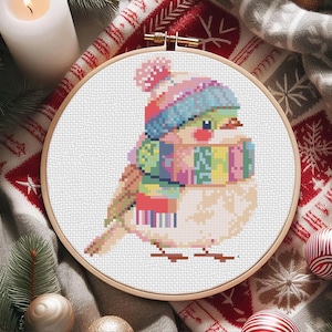 May include: A cross-stitch pattern of a bird wearing a colorful hat and scarf. The bird is white with a yellow beak and black eyes. The hat is pink, blue, and purple, and the scarf is a rainbow of colors.