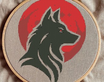 Peut inclure: Broderie représentant la tête d'un loup noir sur fond rouge, encadrée dans un cercle en bois.