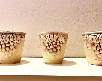 Juego de tres macetas de cerámica vintage con motivos de uvas y hojas de vid.