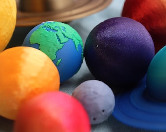May include: A collection of colorful planets, including a blue planet with green continents, a yellow planet with orange stripes, a red planet, a purple planet, a gray planet, and a blue planet with rings.